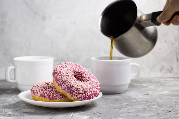 Dwa Pączki Na Talerzu I Kobieca Ręka Wylewają Kawę Z Cezve