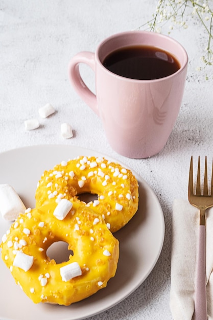 Dwa pączki z piankami i filiżanką herbaty lub kawy