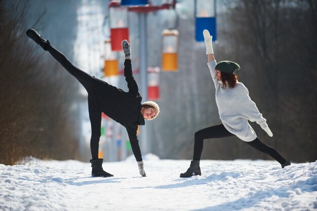 Dwa pięknej młodej kobiety robi joga outdoors w zima parku.