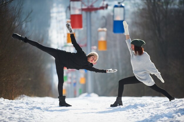 Zdjęcie dwa pięknej młodej kobiety robi joga outdoors w zima parku.