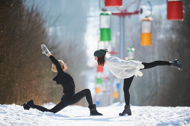 Dwa pięknej młodej kobiety robi joga outdoors w zima parku.