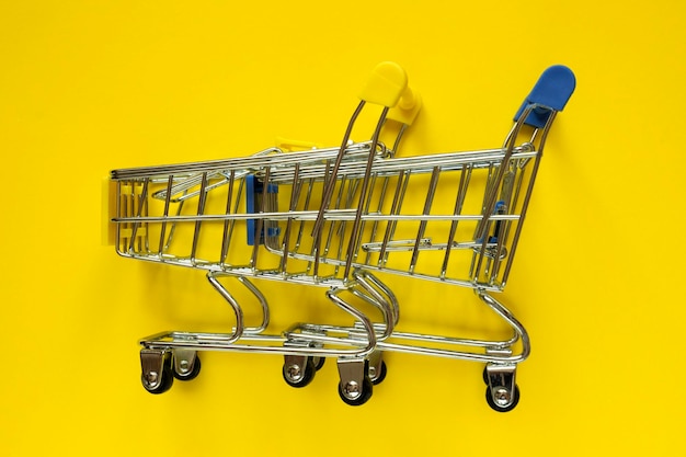 Dwa puste mini wózki w supermarkecie na żółtym tle Koncepcja zakupów Koncepcje sprzedaży