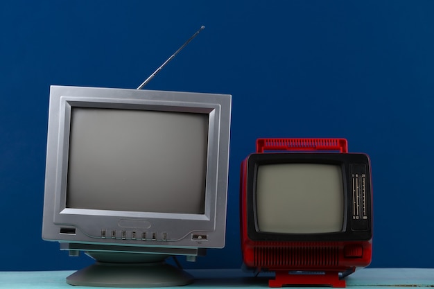 Dwa retro staromodne przenośne telewizory na klasycznym niebieskim tle. Media retro