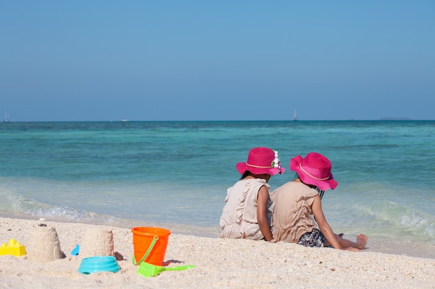 Dwa ślicznej Azjatykciej Małe Dziecko Dziewczyny Siedzi I Bawić Się Z Piaskiem Wpólnie Na Plaży