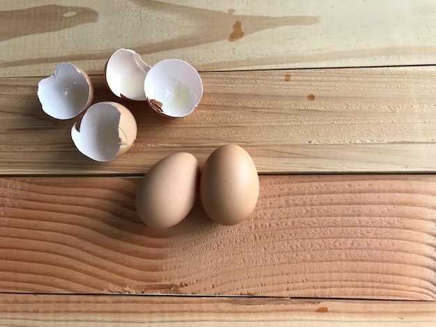 Dwa świeże jaja kurczaka z czterema kawałkami skorup jaj na desce z gumy
