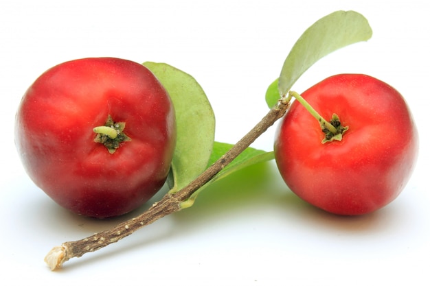 Dwa świeży organicznie Acerola z zielonymi liśćmi, odizolowywającymi na białym tle