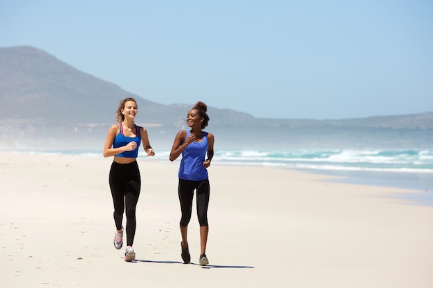 Dwa szczęśliwej młodej kobiety jogging na plaży