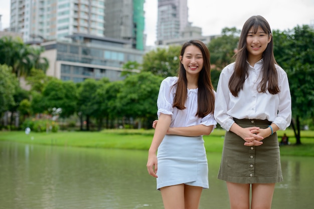 Dwa szczęśliwej młodej pięknej Azjatyckiej nastoletniej kobiety ma zabawę wpólnie w parku