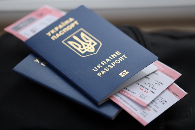 Dwa ukraińskie paszporty biometryczne z biletami lotniczymi na czarnym turystycznym plecaku