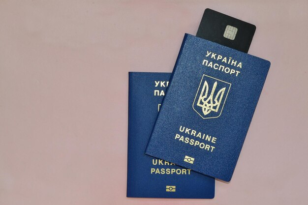 dwa ukraińskie paszporty i karta kredytowa leżą na różowym tle