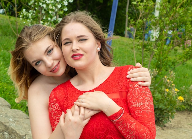Dwa uroczej siostry przytulania Piękne dziewczyny w czerwonych sukniach