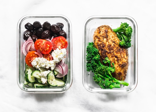 Dwa zdrowe, zbilansowane pudełka na lunch z sałatką grecką pieczoną piersią z kurczaka i brokułami