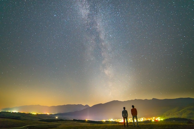 Dwaj przyjaciele stoją na tle gwiazd. pora nocna