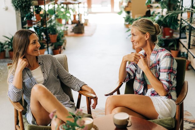 Zdjęcie dwie atrakcyjne młode kobiety rozmawiają w przyjemnej kawiarni