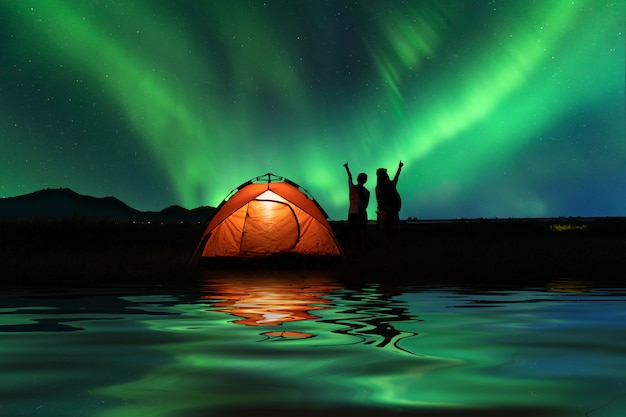 Zdjęcie dwie azjatyckie dziewczyny na zewnątrz camping na wakacje z majestatycznymi zorzy polarnej