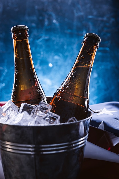 Zdjęcie dwie butelki piwa w wiadrze z lodem i leżącą w pobliżu amerykańską flagą. koncepcja obchodów dnia niepodległości