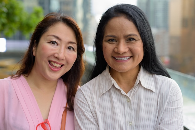 Dwie dojrzałe kobiety azjatyckie razem przed widokiem na miasto
