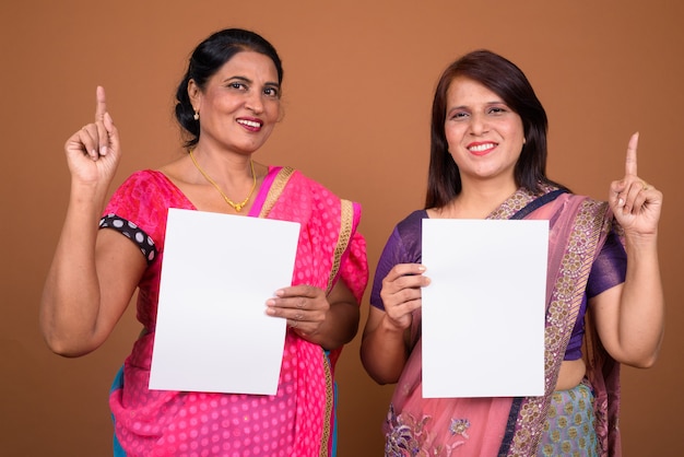dwie dojrzałe kobiety indyjskie ubrane w tradycyjne stroje indyjskie Sari wraz z czystym papierem