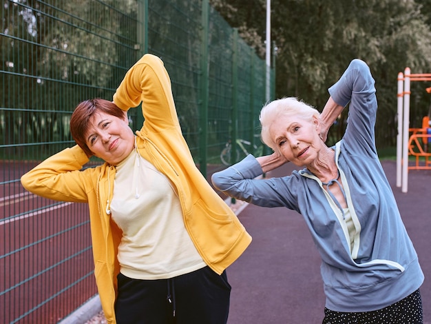 dwie dojrzałe kobiety robiące ćwiczenia sportowe w parku koncepcja zdrowego stylu życia