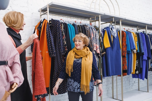 Dwie dojrzałe kobiety wybierają modne ubrania w sklepie odzieżowym Zakupy robią zakupy