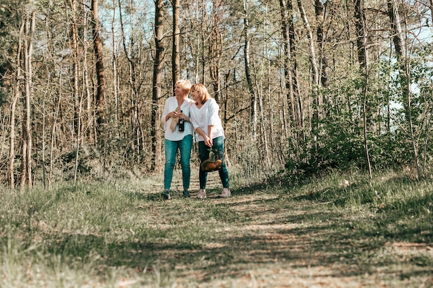 Dwie dojrzałe koleżanki idą przez las. Aktywny styl życia, hobby