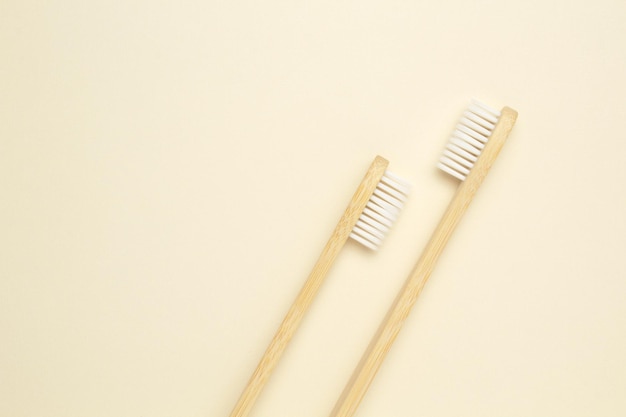 Dwie drewniane bambusowe przyjazne dla środowiska szczoteczki do zębów na beżowym tle Opieka stomatologiczna i koncepcja zero odpadów