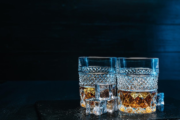 Dwie drogie szklanki whisky z lodem na czarnej kamiennej tacy