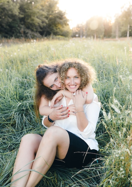 Dwie dziewczyny lesbijki siedzą na trawie w parku i przytulają się. Miłość do osób tej samej płci. OSOBY LGBT