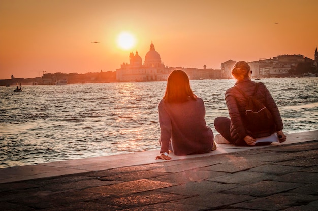 Dwie dziewczyny podziwiają malowniczy zachód słońca nad Santa Maria della Salute w Wenecji.