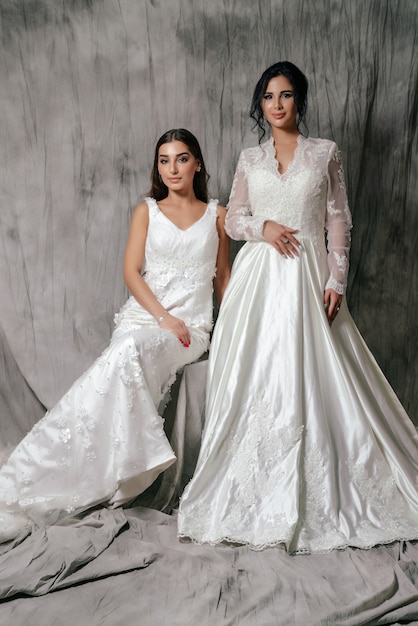 Dwie dziewczyny w portret studio sukni ślubnej na szarym tle