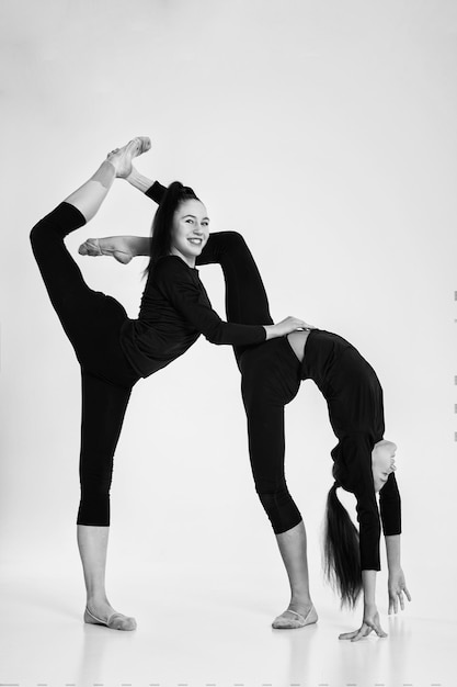 Dwie dziewczyny z gimnastyki artystycznej w body pokazują rozciąganie i zginanie na stojąco