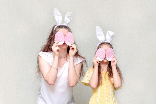 Dwie dziewczyny z uszami królika wielkanocnego zamykają oczy z jajkami wielkanocnymi Wielkanoc jest zabawna