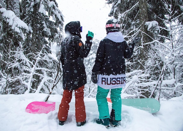 Dwie dziewczyny ze snowboardem w lesie w górach i opady śniegu