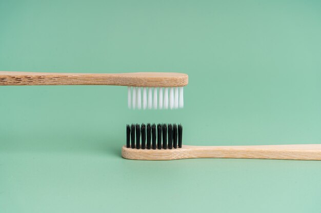 Zdjęcie dwie ekologiczne, antybakteryjne szczoteczki do zębów z drewna bambusowego z biało-czarnym włosiem na jasnozielonym tle. dbanie o środowisko jest na czasie. tolerancja. skopiuj miejsce.
