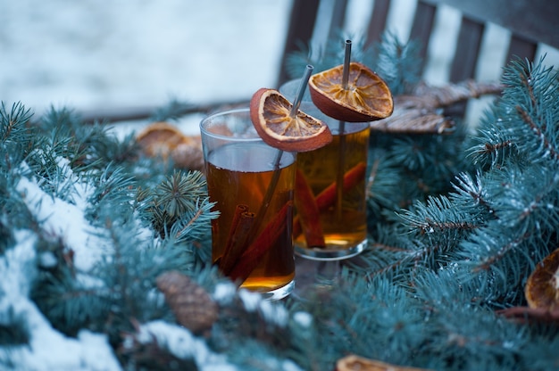 Zdjęcie dwie filiżanki gorącej herbaty z plastrami cynamonu i pomarańczy w świątecznym wieńcu na drewnianej ławce
