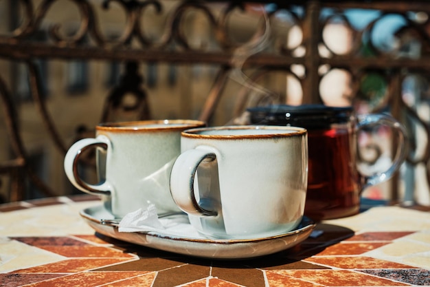 Dwie filiżanki herbaty na zabytkowym stole na starym tarasie para unosi się nad kubkiem gorącego napoju Pomysł na popołudniową herbatę Selektywna koncentracja na filiżance