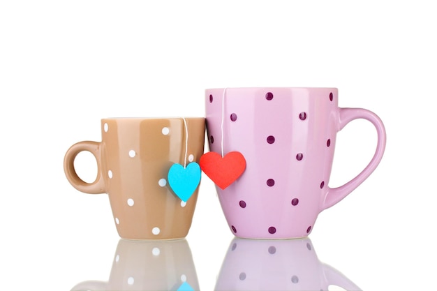 Dwie filiżanki i torebki herbaty z czerwoną i niebieską etykietą w kształcie serca na białym tle