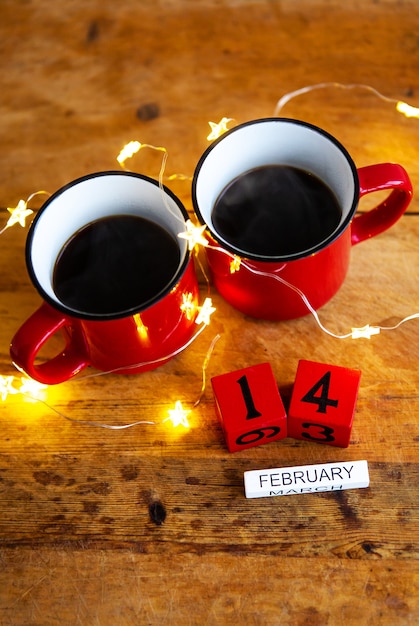 Dwie filiżanki kawy w czerwonych filiżankach na ścianie girland. Poranne śniadanie na Walentynki. Widok z góry.