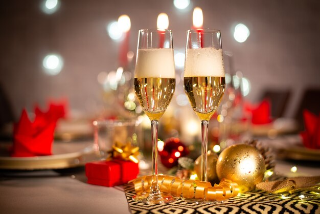 Zdjęcie dwie filiżanki szampana na świątecznym świątecznym stole z czerwoną i złotą błyszczącą dekoracją