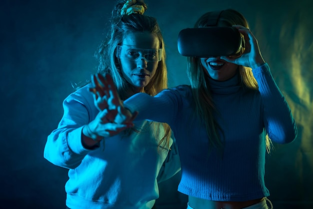 Dwie futurystyczne kobiety w okularach vr patrzące na niebieskie tło metaverse