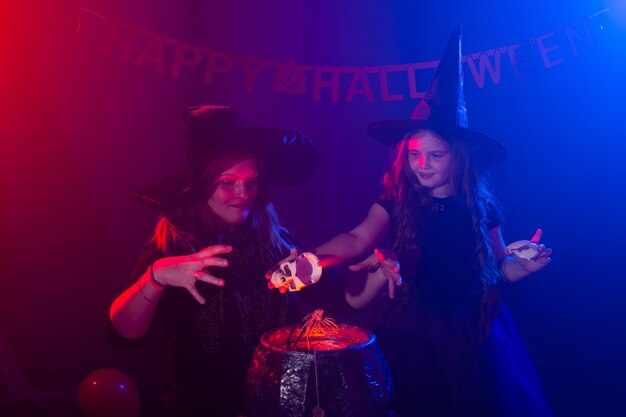 Dwie halloweenowe wiedźmy przygotowują miksturę i wyczarowują w halloweenowej nocy magiczne święta i mistyk