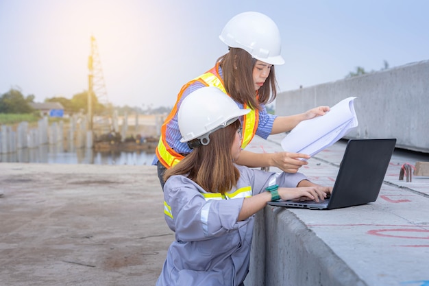 Dwie kobiece przywódca architekta pracy z laptopem i plany na budowie lub placu budowy.