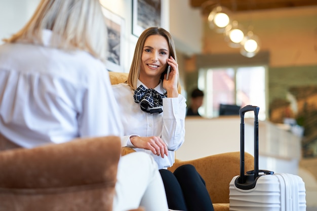 Dwie kobiety biznesu z białą walizką w nowoczesnym hotelowym foyer