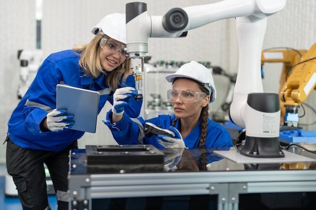 Dwie kobiety inżynier automatyk sprawdzające i kontrolujące maszynę ramienia robota w fabryce