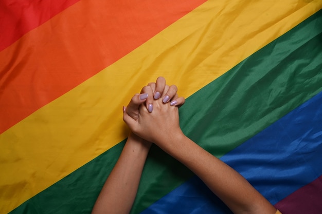Dwie kobiety lesbijek para trzymając się za ręce nad flagą dumy LGBT. Koncepcja LGBT.