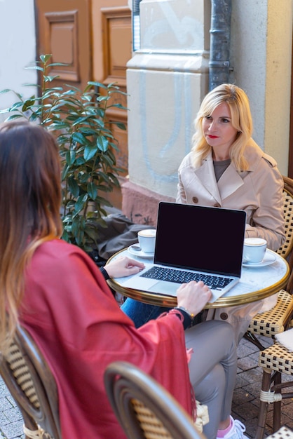 Dwie kobiety na spotkaniu biznesowym w kawiarni współpracują z dziewczynami online
