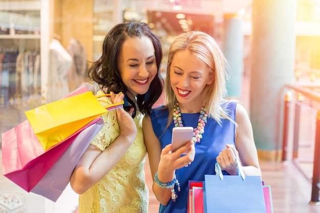 Dwie kobiety patrzące na smartfon podczas zakupów