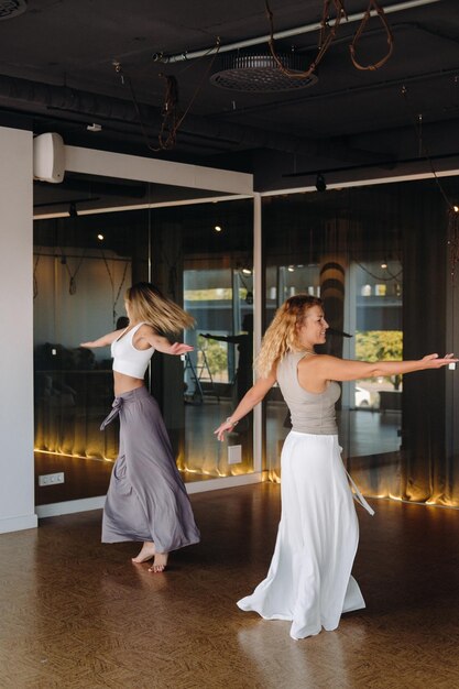 Dwie kobiety w strojach sportowych ćwiczą jogę taneczną na siłowni