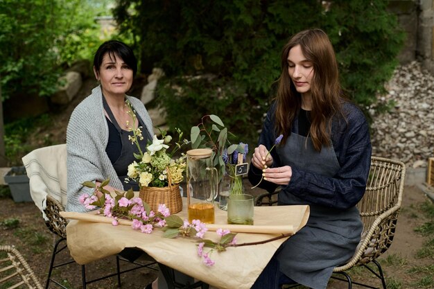 Dwie kwiaciarki mama i córka piją herbatę w ogrodzie