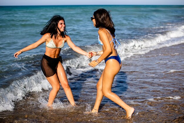 Dwie ładne młode kobiety bawiące się nad morzem w gorący letni dzień